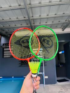 una persona con dos raquetas de tenis en una habitación en Hideout Airbnb, en Pandi