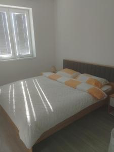 una camera da letto con un letto con lenzuola bianche e una finestra di Apartman Plaza 9 a Veliko Gradište