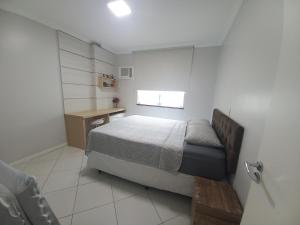 um pequeno quarto com uma cama e uma secretária em Excelente apartamento em Itapema