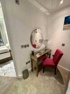 1 dormitorio con escritorio, silla roja y espejo en Gunwharf Quays Harbour Apartments, en Portsmouth