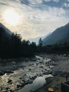 a river with rocks in the middle of a mountain at Kasol Village Camp in Kasol