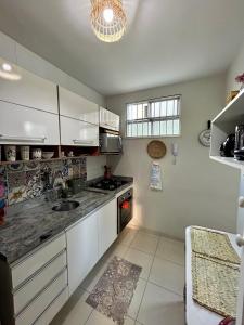 a kitchen with white cabinets and a stove top oven at Apartamento Oxe! Tô na Bahia in Salvador