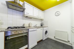 a kitchen with a stove and a washer and dryer at The Whitecross Street Apartment in London