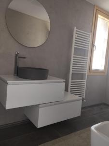 La salle de bains blanche est pourvue d'un lavabo et d'un miroir. dans l'établissement Casa vacanze il bibbiere, à Olgiate Comasco