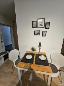 a dining room table with white chairs and a white wall at Ulmer Nestchen in Ulm +2 photos