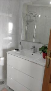 a white bathroom with a sink and a mirror at Piso Areal con vistas al mar in Portonovo +9 photos