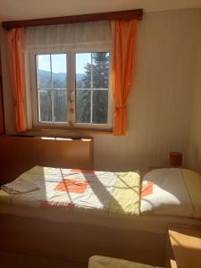 a bedroom with a bed and a window with orange curtains at Monte Lope in Bystřice pod Lopeníkem