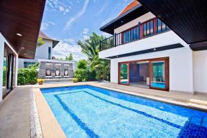 a swimming pool in front of a house at Tropicana Pool Villa in Jomtien Beach