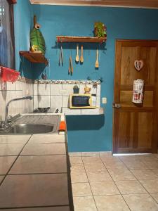 - une cuisine avec un évier et un mur bleu dans l'établissement Surf House, à Sámara