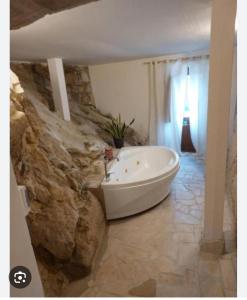 a bathroom with a white tub and a stone wall at hotel scaffe in Pennapiedimonte