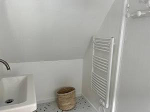 Baño blanco con lavabo y cesta en Charmant T4 entièrement rénové ! en Lannion