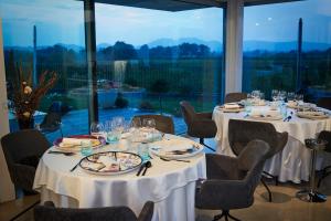 un comedor con mesas y sillas con manteles blancos en House Iaquin en Dobrovo