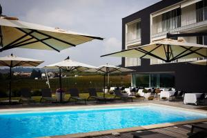 a swimming pool with chairs and umbrellas next to a building at House Iaquin in Dobrovo