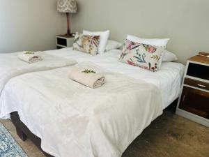 2 camas en una habitación con sábanas y almohadas blancas en Namgate Guesthouse en Grünau