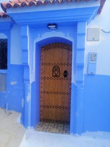 um edifício azul com uma porta de madeira à frente em Dar issam em Chefchaouen