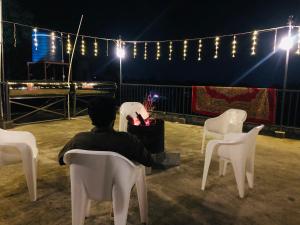 a man sitting in a white chair at night at Hayat Residency - The Quarry Lake in Kalpetta