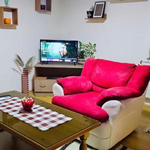a red couch in a living room with a table at Apartman 053 in Doboj