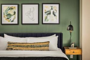 a bedroom with green walls with a bed and three framed pictures at Urban Gallery Loft - King Bed - Larimer Square in Denver
