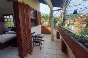 een slaapkamer met een balkon met een bed en stoelen bij Espaço inteiro: casa Manguinhos/Geribá in Búzios