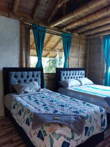 two beds in a room with blue curtains at La Tebaida Posada Rural in Ubaque