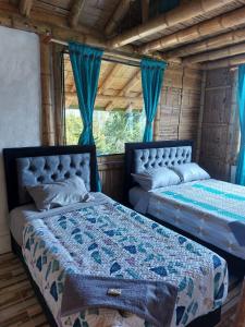 two beds in a room with blue curtains at La Tebaida Posada Rural in Ubaque