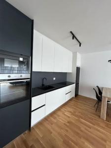 uma cozinha com armários brancos e um frigorífico preto em Arberia Sunshine and Smiles 2 em Pristina
