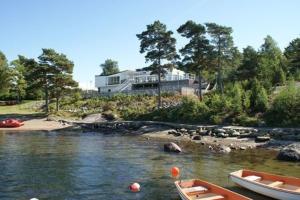 dwie łodzie na rzece z domem w tle w obiekcie Hällestrand Apartment 32 w mieście Strömstad