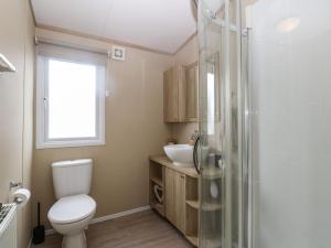 un baño con inodoro y lavabo en Seafront Holiday Home 2, en Pwllheli 20 fotos más