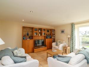 a living room with two white couches and a tv at Sunshine Cottage in Seahouses