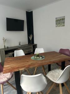 une salle à manger avec une table en bois et des chaises blanches dans l'établissement FeWo Akri, à Ribnitz-Damgarten