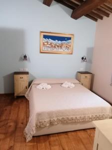 a bedroom with a bed with white sheets and wooden floors at CASALE ANTONELLA in Bastia Umbra