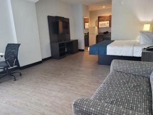 a hotel room with a bed and a couch and a tv at Studio 6 Gonzales TX in Gonzales