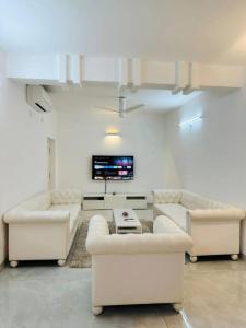 a living room with two white couches and a tv at Luxurious Independent villa in Gachibowli in Hyderabad