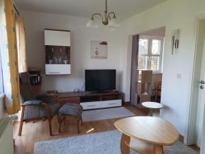 ein Wohnzimmer mit einem TV und einem Tisch in der Unterkunft Sommerhaus in Eggstedt