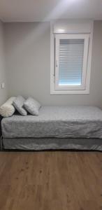 a bed sitting in a room with a window at Apartamento con vistas al río in Betanzos