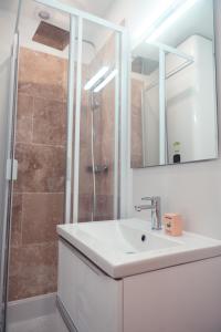 a white bathroom with a sink and a shower at Le Gamay Appartement 6 personnes in Tours