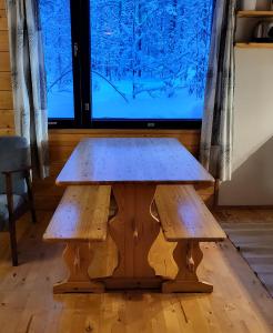 un tavolo in legno con due panche davanti a una TV di Mäntymajat ad Äkäslompolo