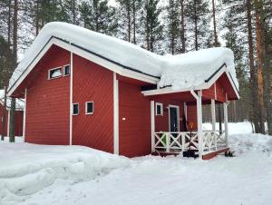 una casa roja con nieve encima en Mäntymajat, en Äkäslompolo