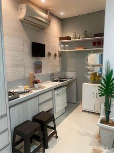 cocina con fregadero y encimera con taburetes en Alugo flat suítes mobiliado com área de lazer, en Araguaína