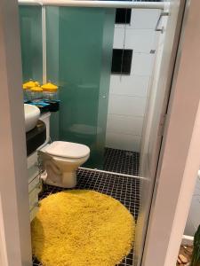 a bathroom with a toilet and a yellow rug at Alugo flat suítes mobiliado com área de lazer in Araguaína