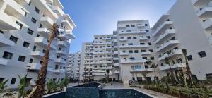 ein großes Apartmenthaus mit einem Pool davor in der Unterkunft Zenata ocean park appartement in Mohammedia