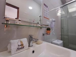 a white bathroom with a sink and a mirror at Arena Hostal in Paracas