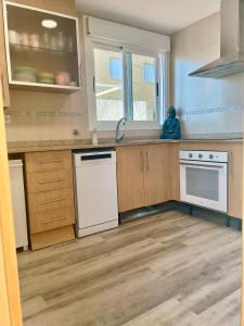 una cocina con electrodomésticos blancos y armarios de madera en Apartamento en primera linea frontal al mar, en El Borseral
