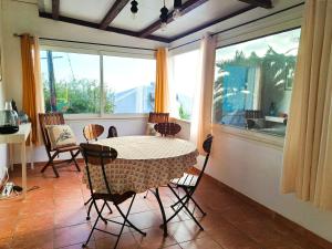 ein Esszimmer mit einem Tisch, Stühlen und einem Fenster in der Unterkunft Ti Caz Marley - Bassin Manapany-Les-Bains in Saint-Joseph