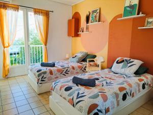 2 Betten in einem Zimmer mit orangefarbenen Wänden in der Unterkunft Ti Caz Marley - Bassin Manapany-Les-Bains in Saint-Joseph