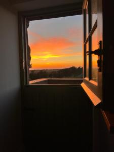 an open window with a view of a sunset at Cwtch Lackerlee in Haverfordwest
