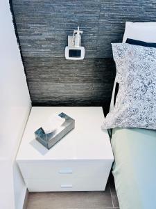 a white nightstand next to a bed with a clock on it at BB SAN SIRO in Milan