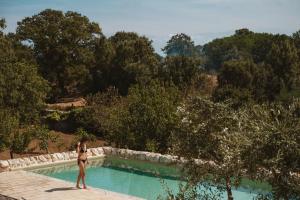 Eine Frau im Bikini steht neben einem Pool. in der Unterkunft i Trulli di Figazzano in Locorotondo