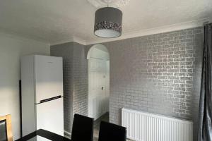 uma cozinha com 2 cadeiras e uma parede de tijolos brancos em M6 Jct 10, 2 Bed House Wolverhampton-Walsall em Willenhall