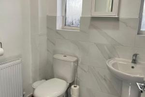Baño blanco con aseo y lavamanos en M6 Jct 10, 2 Bed House Wolverhampton-Walsall en Willenhall